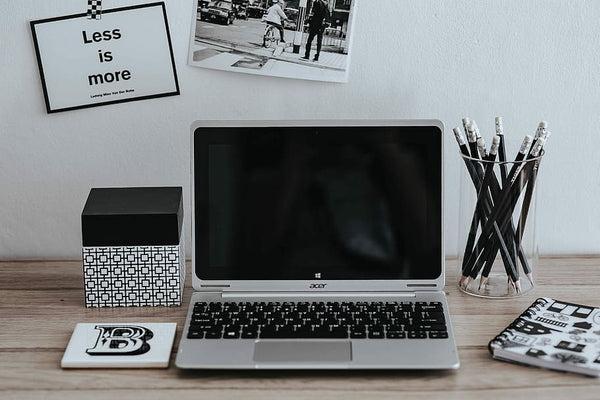 mesa de trabalho com laptop, caderno, porta lápis, caixas e imagens
