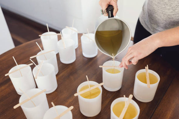 pessoa colocando cera em potes de velas mostrando como fazer velas aromáticas para vender