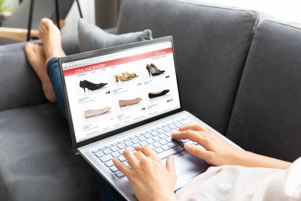 mulher compra sapatos online no laptop enquanto descansa no sofá