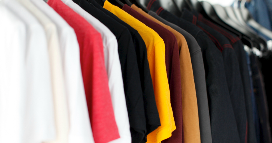 Como abrir uma loja de camisetas: fotografia com várias camisetas, de várias cores, em cabides.