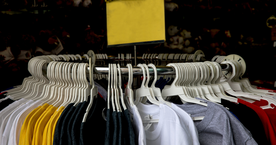 Como abrir uma loja de camisetas: uma arara circular de loja, com várias camisetas de malha penduradas em cabides