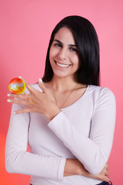 Foto do artigo sobre empreendedorismo feminino mostra a fundadora da marca Lumma, Aline Azar, diante de um fundo rosa, segurando um disco menstrual colorido. Aline é uma mulher de cabelos escuros e liso e veste uma blusa branca de manga comprida.