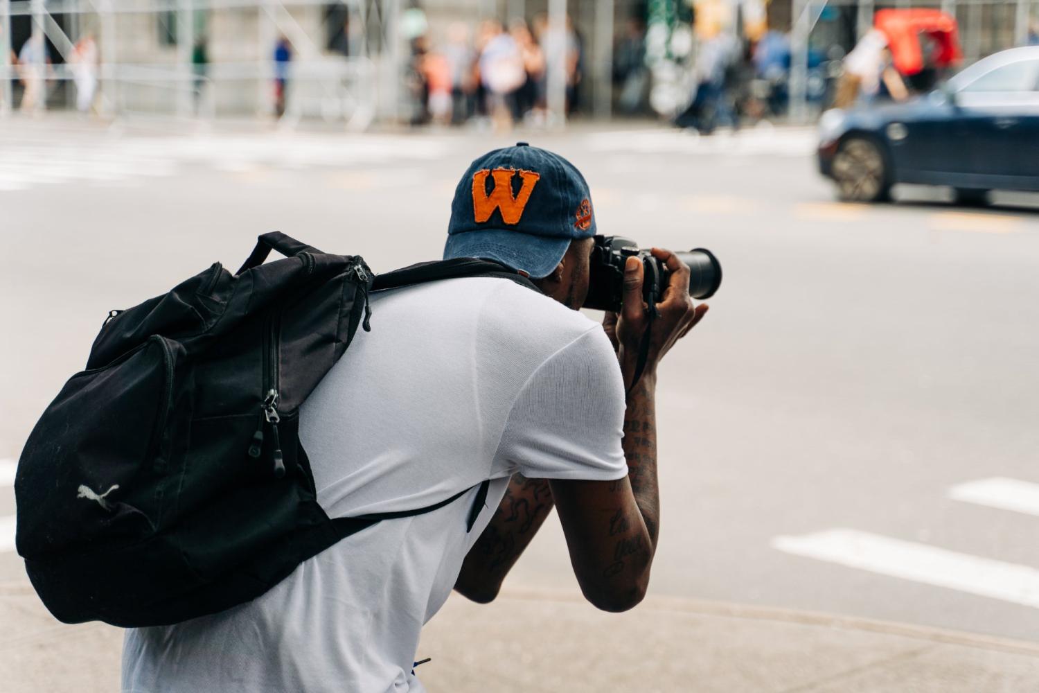 Um jovem fotografando uma rua da cidade