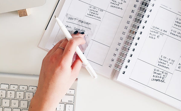 Mãos anotando em um cronograma representando o calendário para campanha dia das mães