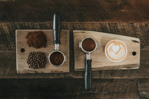 Tábua de madeira com café em grãos, em pó e café passado, representando um clube de assinatura de café