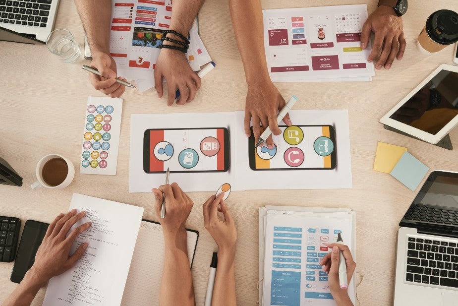 Mãos escrevendo em cima de uma mesa com gráficos e ilustrações, representando a estratégia de marketing de influência