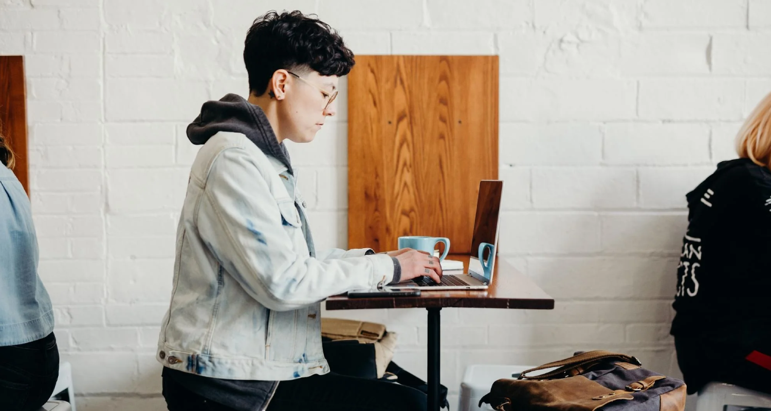 Como abrir um e-commerce - mulher à mesa com seu computador em uma cafeteria