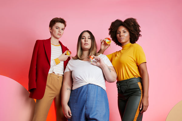 Foto de empreendedorismo feminino mostra três mulheres, uma ao lado da outra, cada uma delas segurando um disco menstrual colorido.