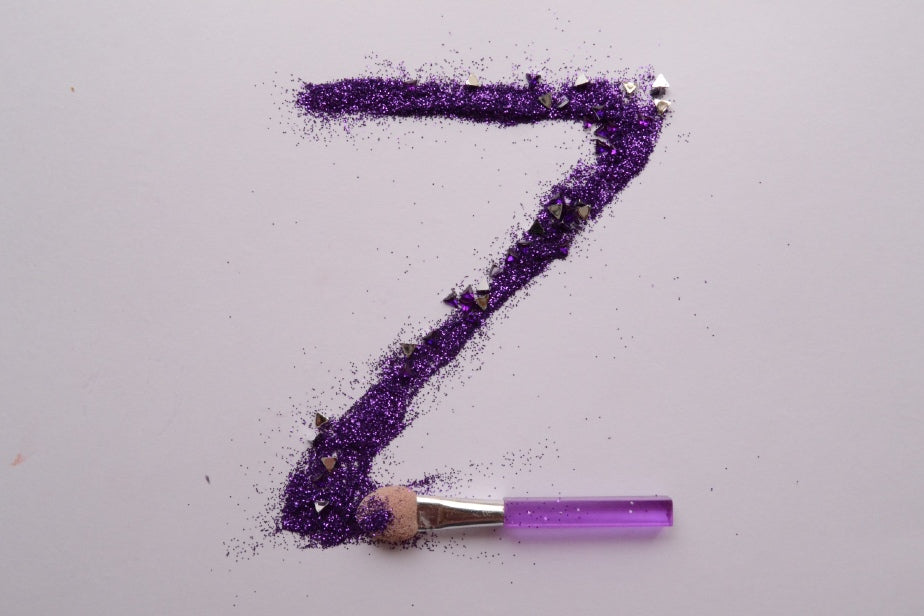 Letra Z desenada com purpurina roxa com pincel de maquiagem ao lado