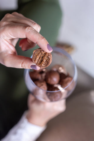 Foto de ideias para Páscoa mostra uma pessoa segurando uma taça de vidro e, dentro da taça, há trufas de chocolate.