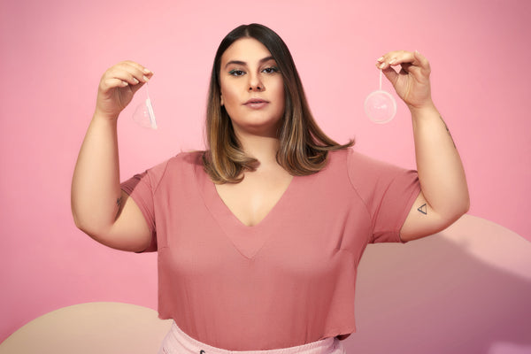 Foto de artigo sobre mulheres empreendedoras mostra uma mulher de camiseta rosa, segurando um disco menstrual transparente em cada mão.