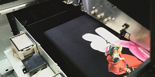 Foto de impressão por demanda mostra o processo de impressão de estampas em camisetas pela Reserva Ink.