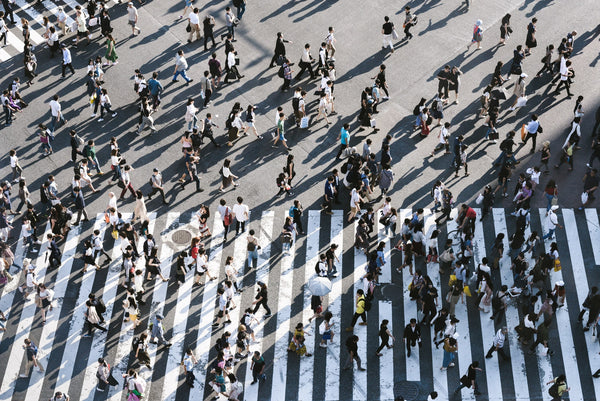 Foto para texto de tráfego pago mostra uma avenida movimentada vista de cima. Na foto, há uma faixa de pedestres onde tem dezenas de pessoas cruzando a avenida.