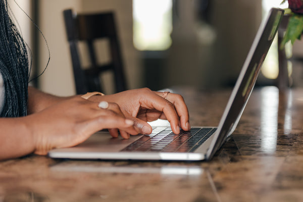 um par de mãos digitando em um laptop