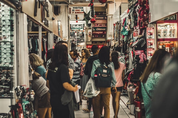 Foto em alusão ao tráfego pago mostra um centro comercial no Brasil, onde há um corredor estreito com lojas de ambos os lados e, no corredor, há diversas pessoas transitando. 