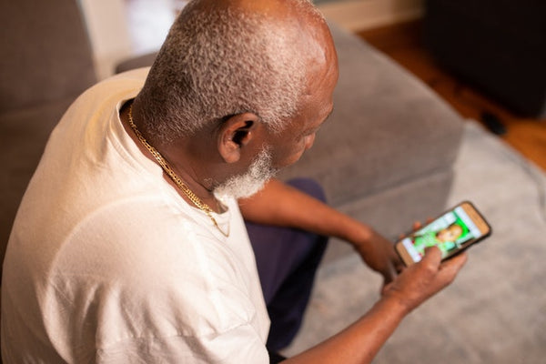 Foto mostra uma pessoa de lado, sentada em um sofá, usando o smartphone para mandar mensagens no WhatsApp Business.