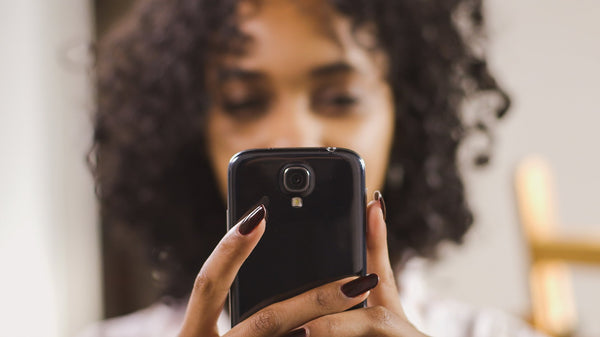 Mulher segura telefone celular na altura dos olhos