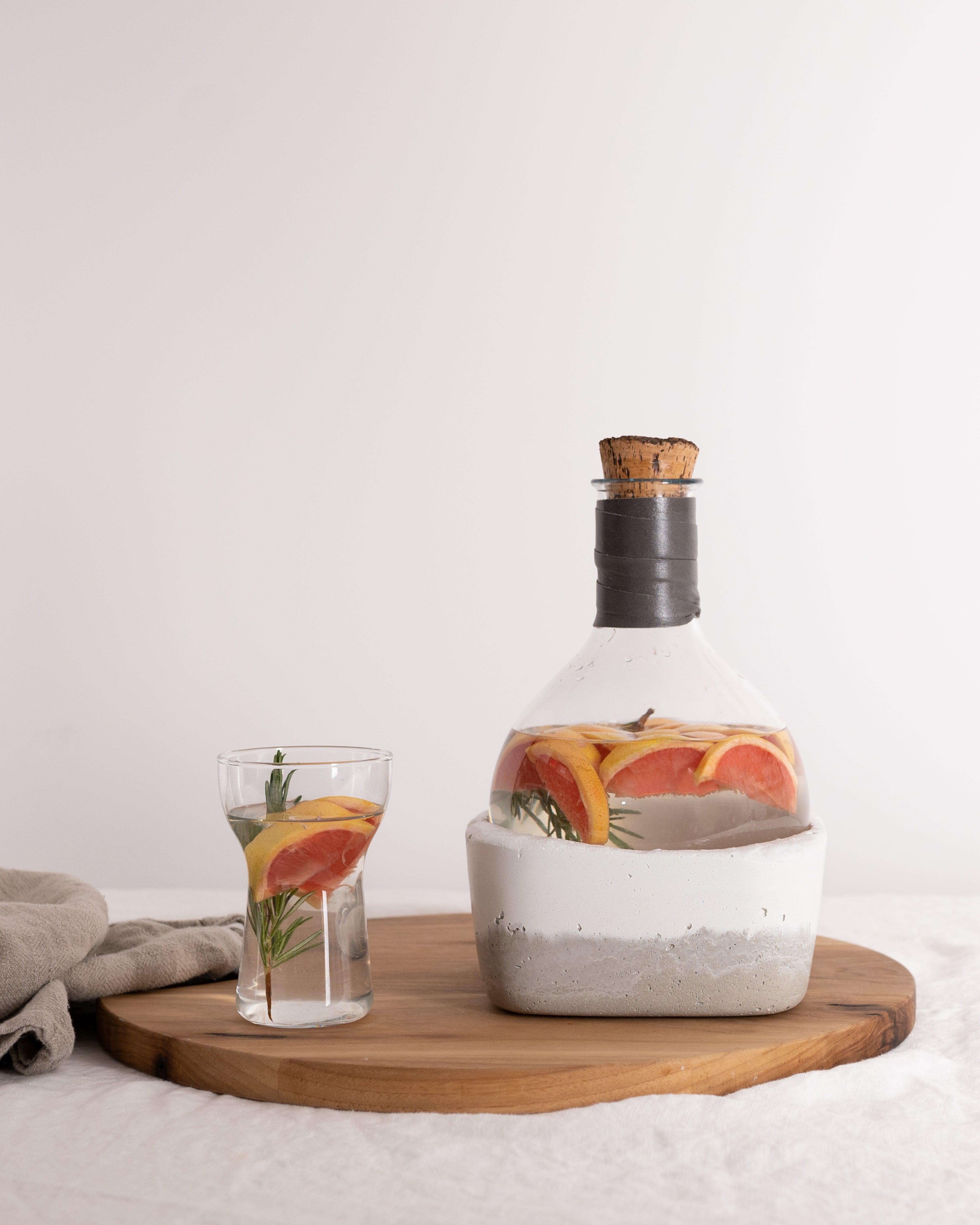 Rock Bottom 2.0 concrete wine decanter with water infused with grapefruit wedges and rosemary sprigs by Studio50