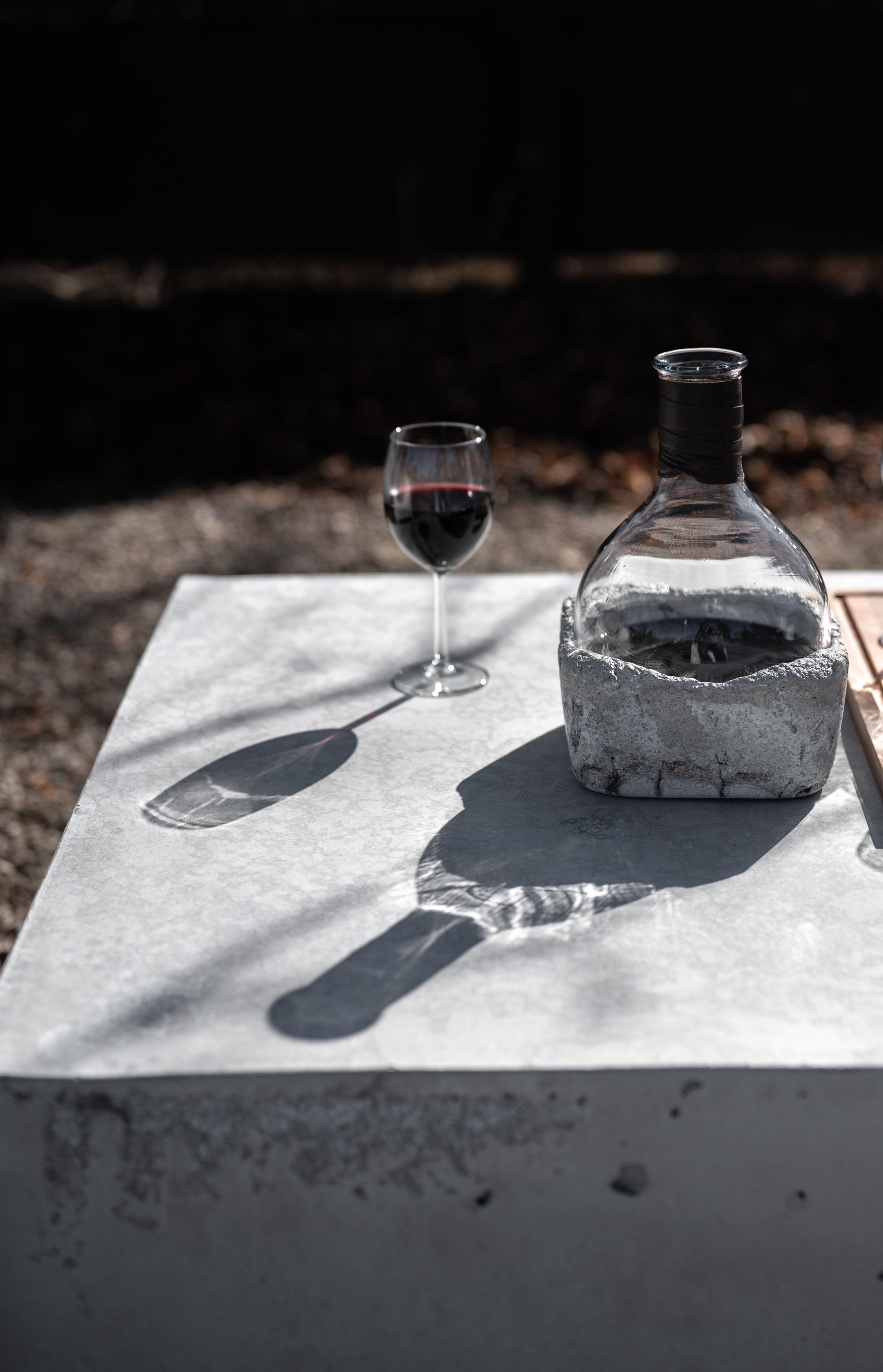 outside sun reflecting shadows from Rock Bottom wine decanter filled with red wine by studio50