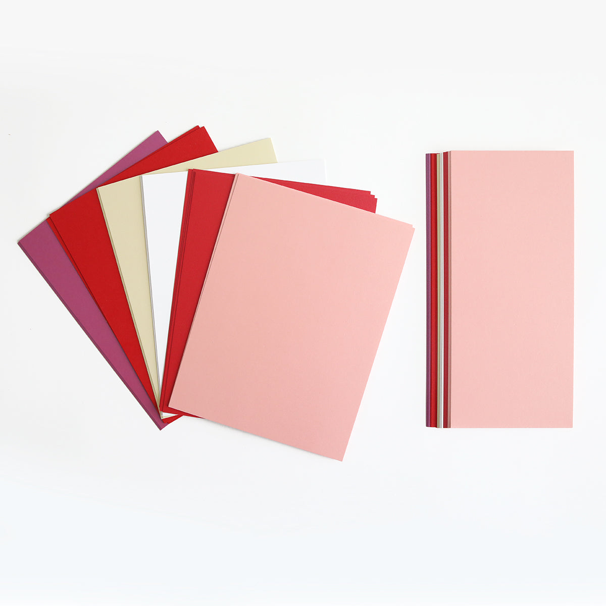 The Luxury Shimmer Cardstock Bundle features pastel and bold sheets in pink, red, lavender, cream, and white—perfect for die cut projects or handmade cards—arranged in two stacks on a white background.