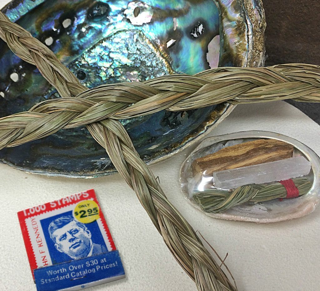 Burning sweet grass is used in clearing personal spaces of negativity, and its scent is memorable. The crystal in the small shell at right is Selenite, which is believed to offer good luck and protection