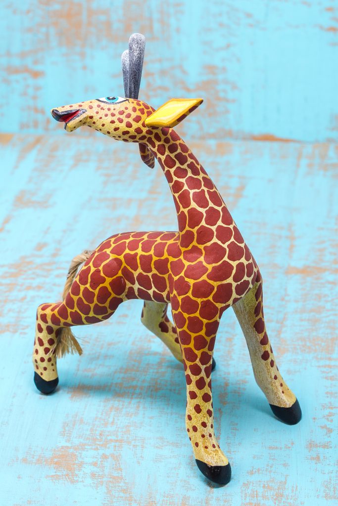 A smiling Oaxacan carved giraffe in bright colors.