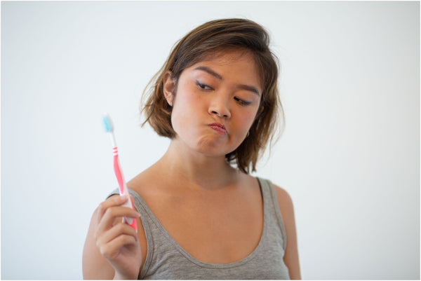 doubtful woman holding a toothbrush