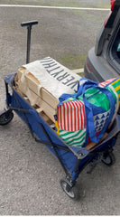 a small 4 wheel wagon, with a handle to pull it with, is filled with bags.