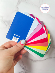 A hand holds a fan of swatchos - credit card sized colour swatch cards - which are all bright colours representing a spring colour palette.