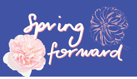 A blue background with 2 Dahlia drawings - one full colour in pinks, the other a pink line drawing, with the words Spring Forward handwritten across the centre.