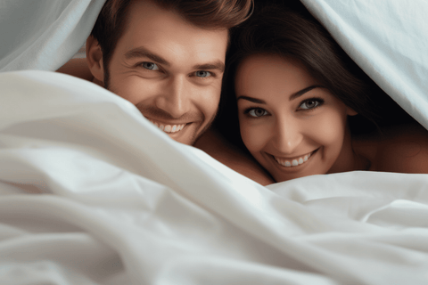 cute couple lying on the bed peeking out from under the blanket and smiling