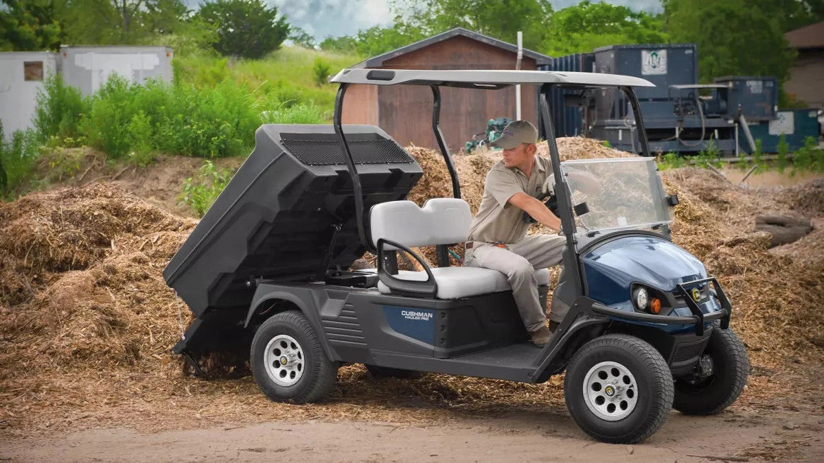 EZGO Hauler Electric cart with a man sitting in the front seat unloading a load of mulch in the tip tray