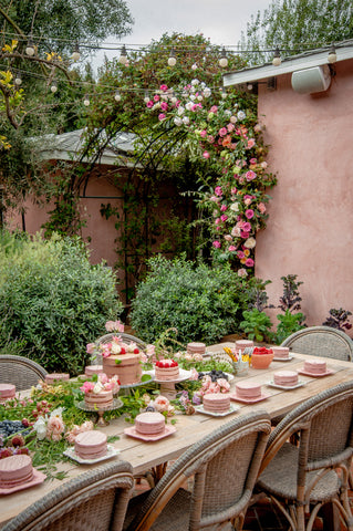 table and chairs set with pink cakes and flowers