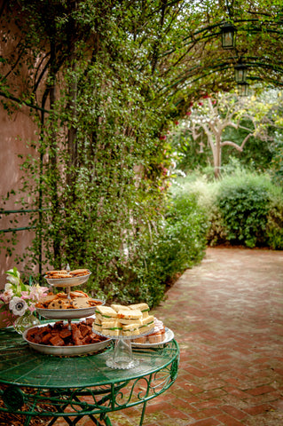 baked goods and tea sandwiches on a table in a garden arch walkway