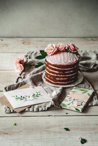 A cake with pink frosting and flowers beautifully displayed on a table