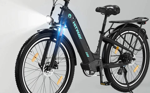 Angled view of the HITWAY BK16 electric bicycle featuring front LED headlight illumination, a sturdy black frame, and rear cargo rack, perfect for urban commuting and night riding.