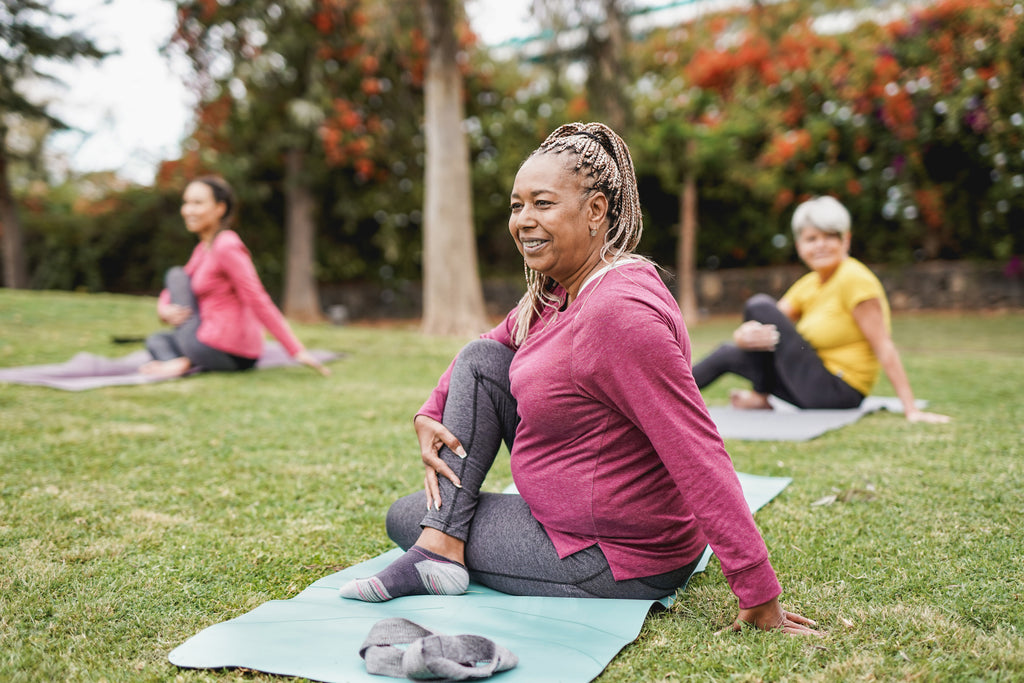 Women doing yoga exercise with social distance for coronavirus outbreak at park outdoor