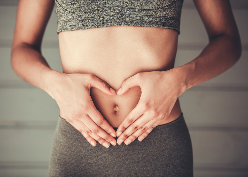 Woman in sportswear showing heart on her stomach