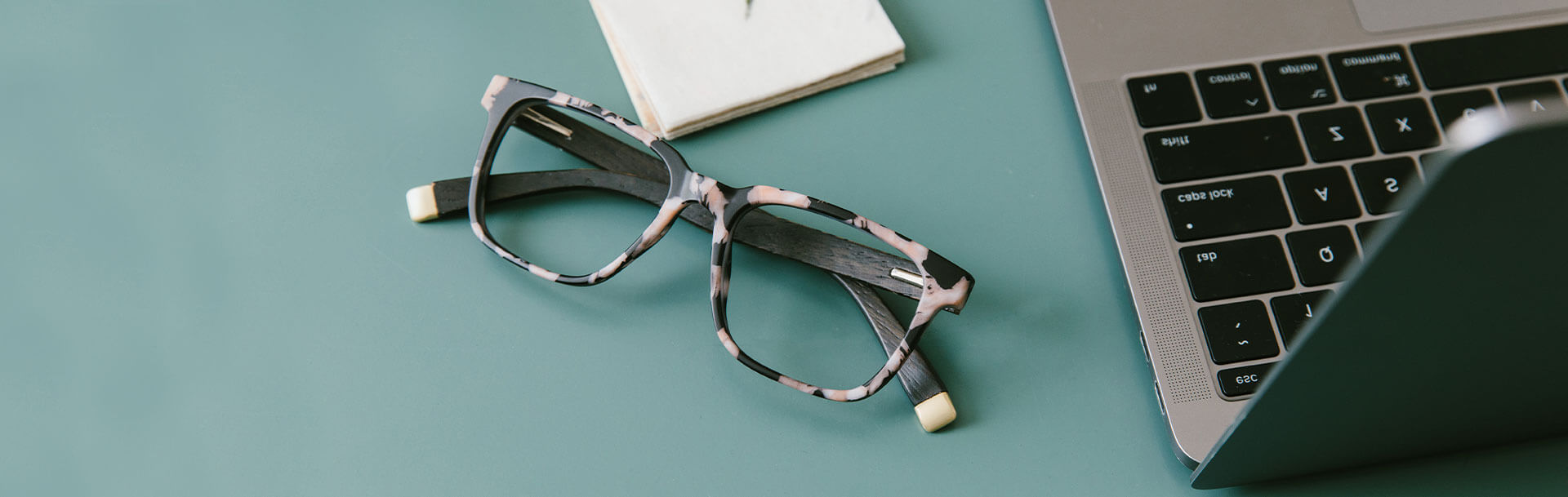 Peepers Harvest Blue Light Glasses Sitting Flat on Table Next to Computer