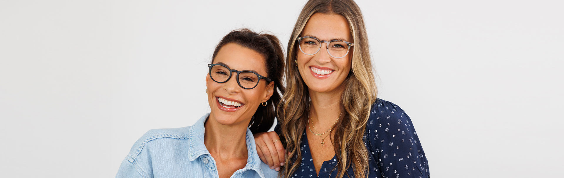 Two woman standing against plain background both wearing Peepers Blue Light Glasses Rumor