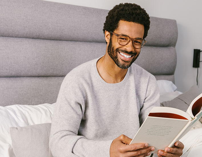 Man Sitting Up In Bed Reading Wearing Peepers Reading Glasses Orion