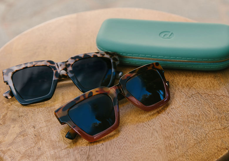 Peepers Sunglasses Out Of Office laying flat on surface overlapping Peepers Silicone Case