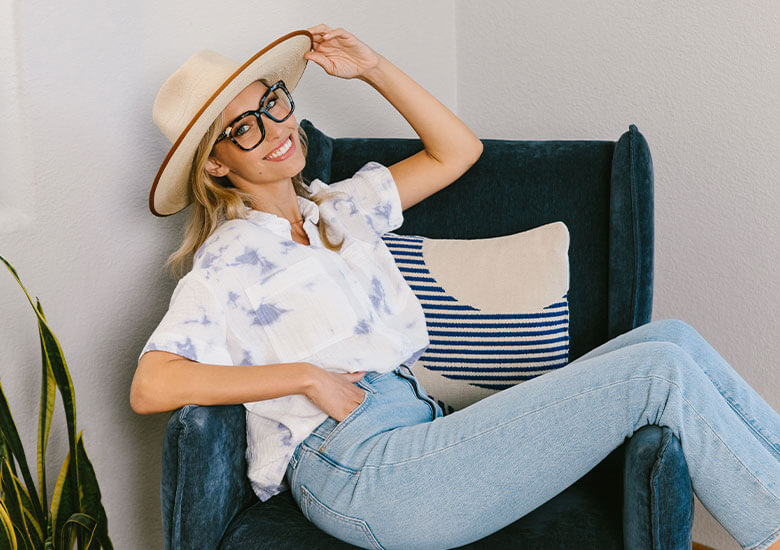 Woman sitting on chair wearing Peepers Blue Light Reading Glasses Next Level