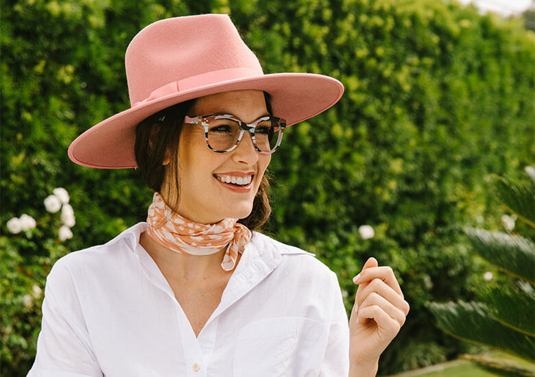 Woman in Pink Hat Standing Outside Wearing Peepers Blue Light Reading Glasses Oasis
