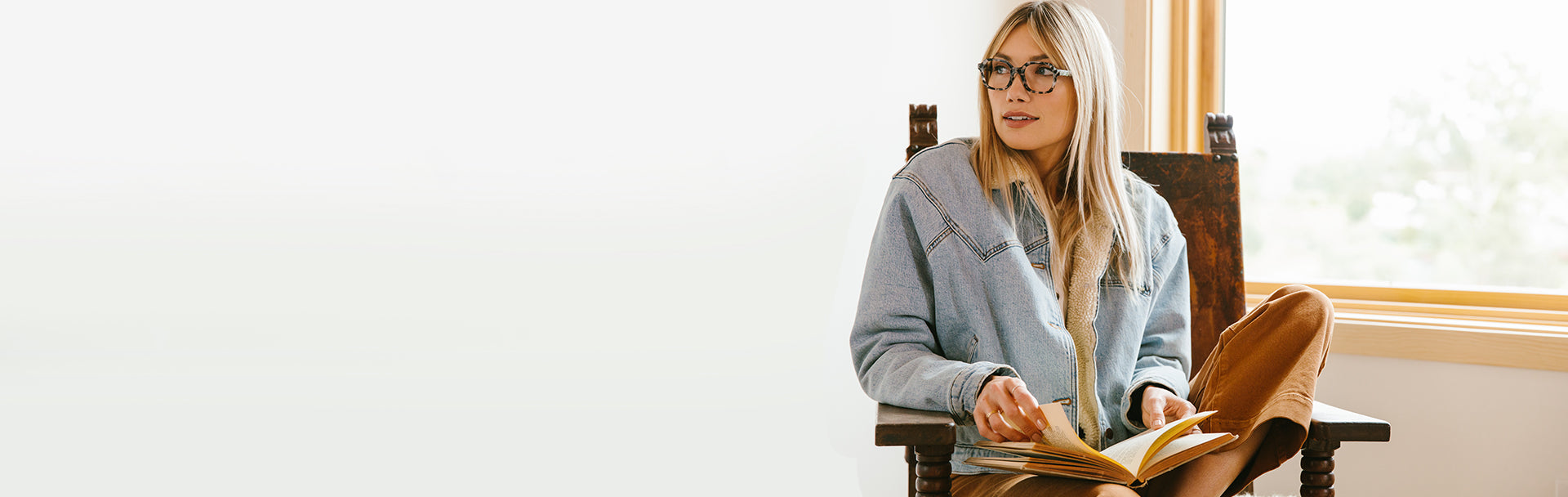 Blonde woman reading a book while wearing Peepers reading glasses