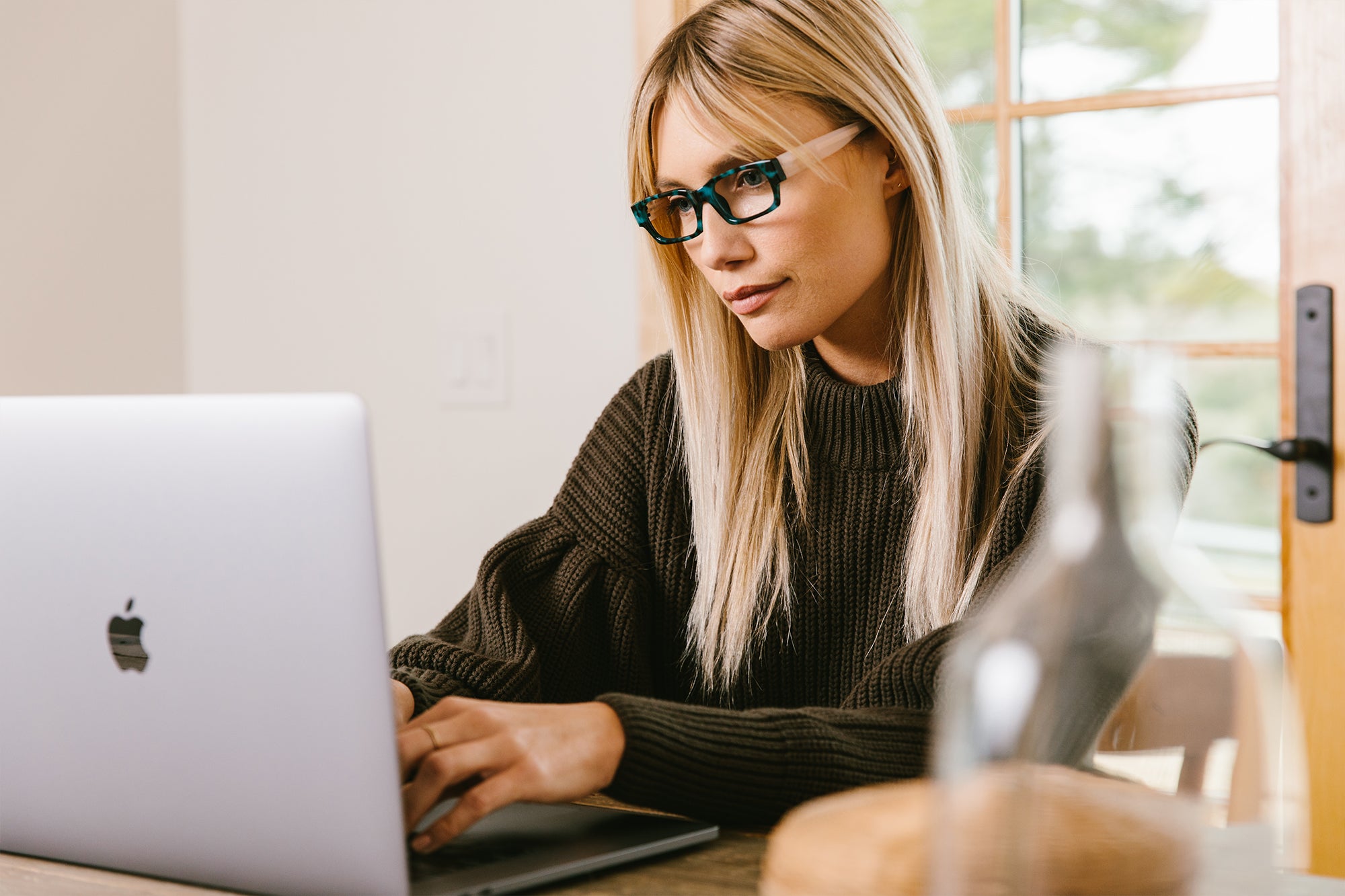 Woman wearing Peepers blue light reading glasses while working on laptop