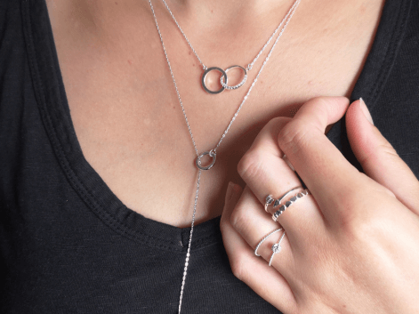 Woman wearing a selection of silver necklaces and ring stacks