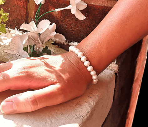 woman wearing a pearl bead bracelet leaning on a wall