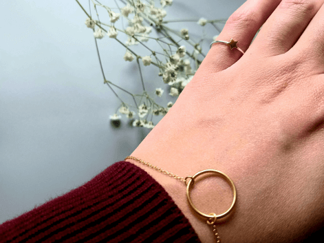 Woman wearing a gold circle bracelet on a floral background