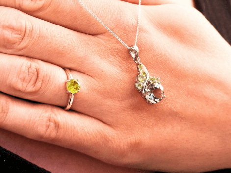 woman wearing a peridot solitaire ring and a fancy peridot and lemon quartz pendant